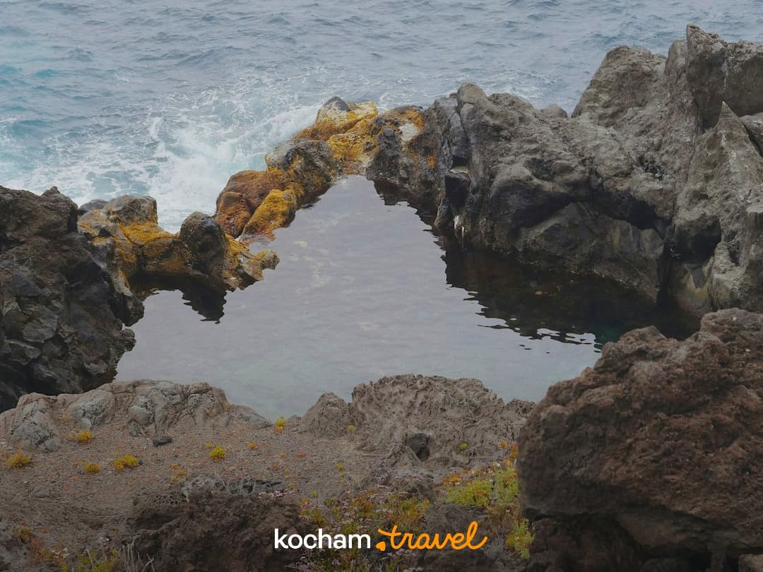 Naturalny basen wulkaniczny w kształcie serca, ocean, skaliste wybrzeże.