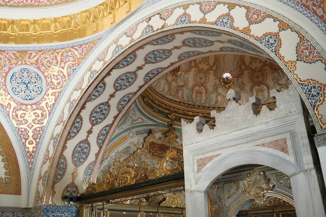 Bogato zdobione wnętrze z ozdobnymi łukami i złotymi detalami architektury osmańskiej.