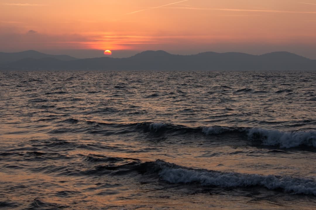 Zachód słońca nad spokojnym oceanem i falami.