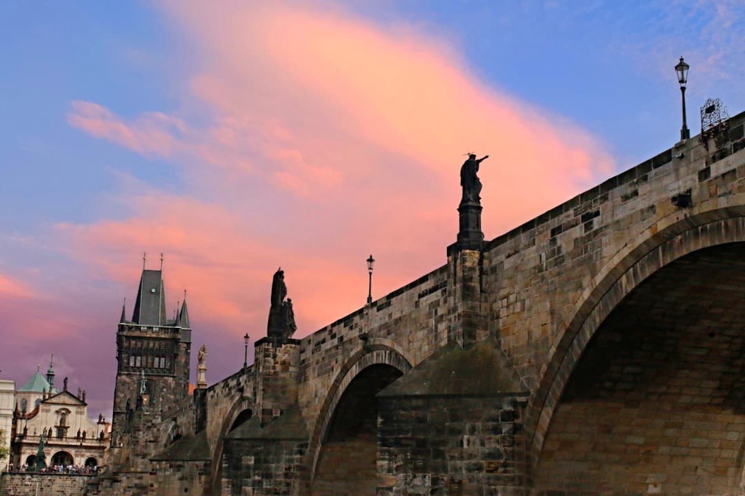 Praski Most Karola, posągi, zabytkowa architektura o zachodzie słońca.