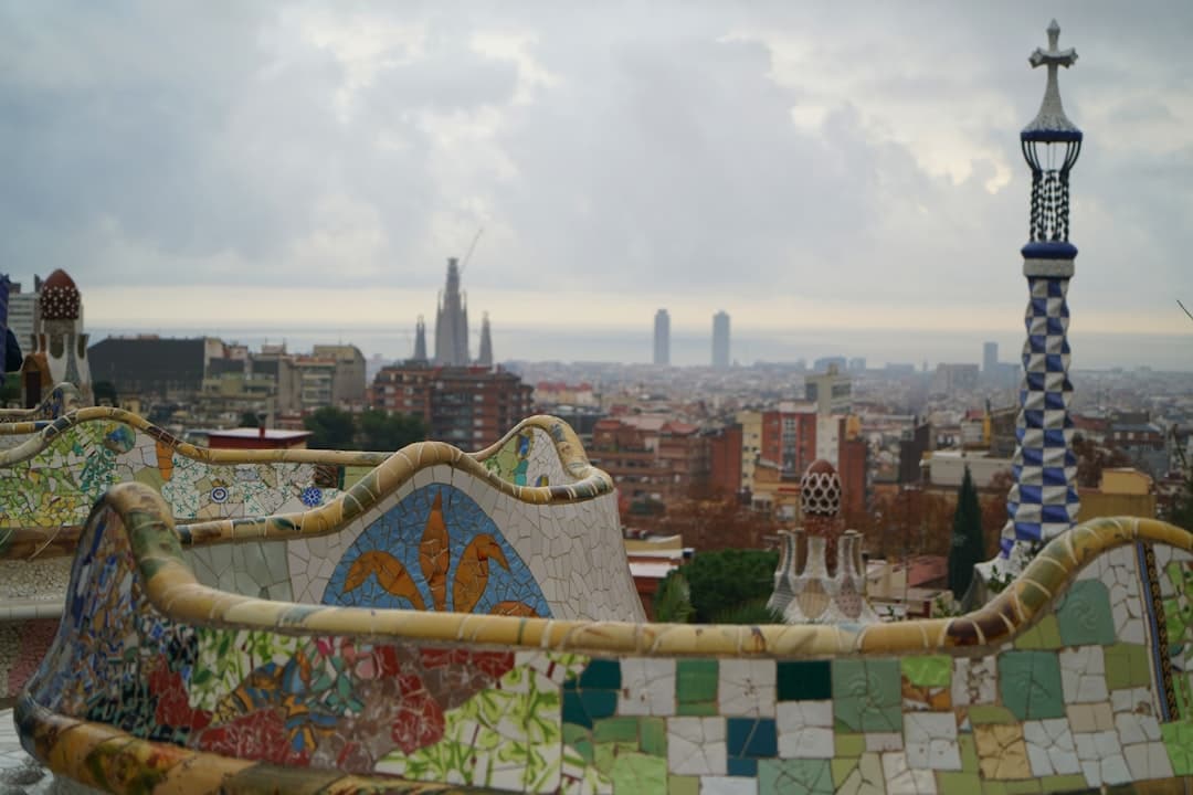 Kolorowe mozaiki Parku Güell z panoramą Barcelony i Sagradą Familią.
