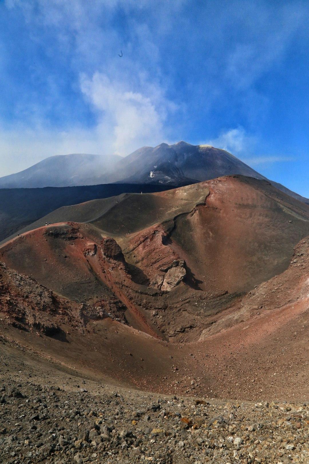 Aktywny wulkan Etna, dymiący szczyt, czerwone kratery boczne.