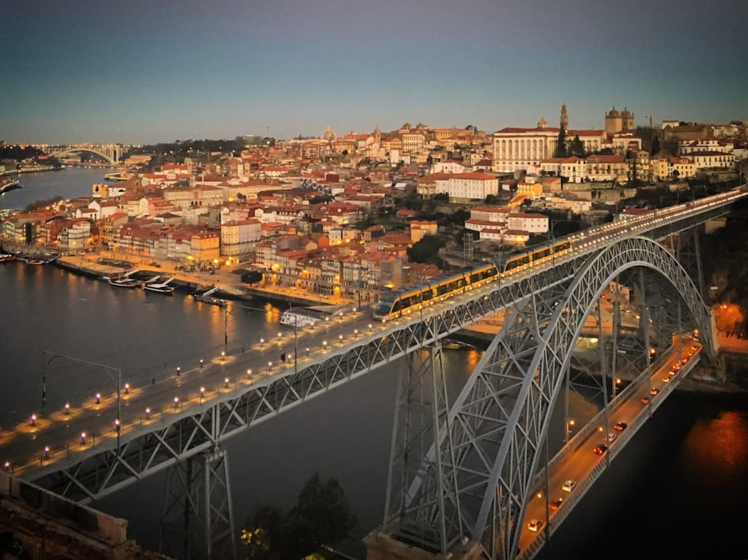 Oświetlony most Dom Luís I, pociąg, rzeka Douro i panorama Porto.