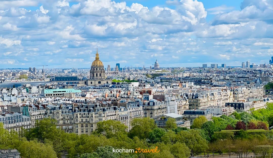 Słoneczna panorama Paryża z Les Invalides i zielonymi drzewami.