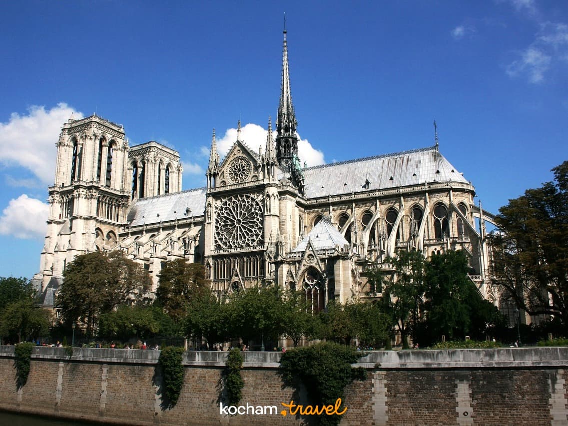 Gotycka Katedra Notre Dame w Paryżu nad Sekwaną w słońcu.