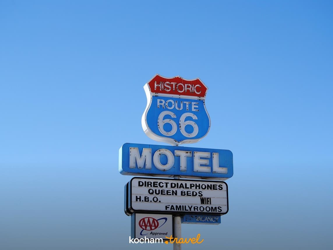 Zabytkowy znak motelu Route 66 pod błękitnym niebem.