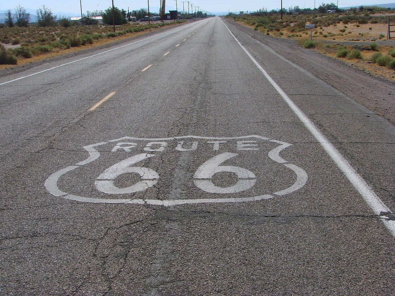 Znak Route 66 na asfaltowej drodze, suchy krajobraz.