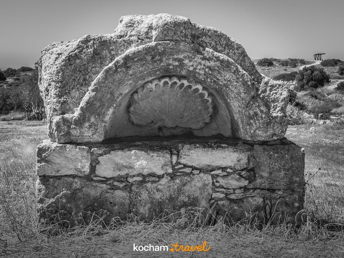 Starożytny kamienny pomnik z rzeźbioną muszlą na stanowisku archeologicznym.