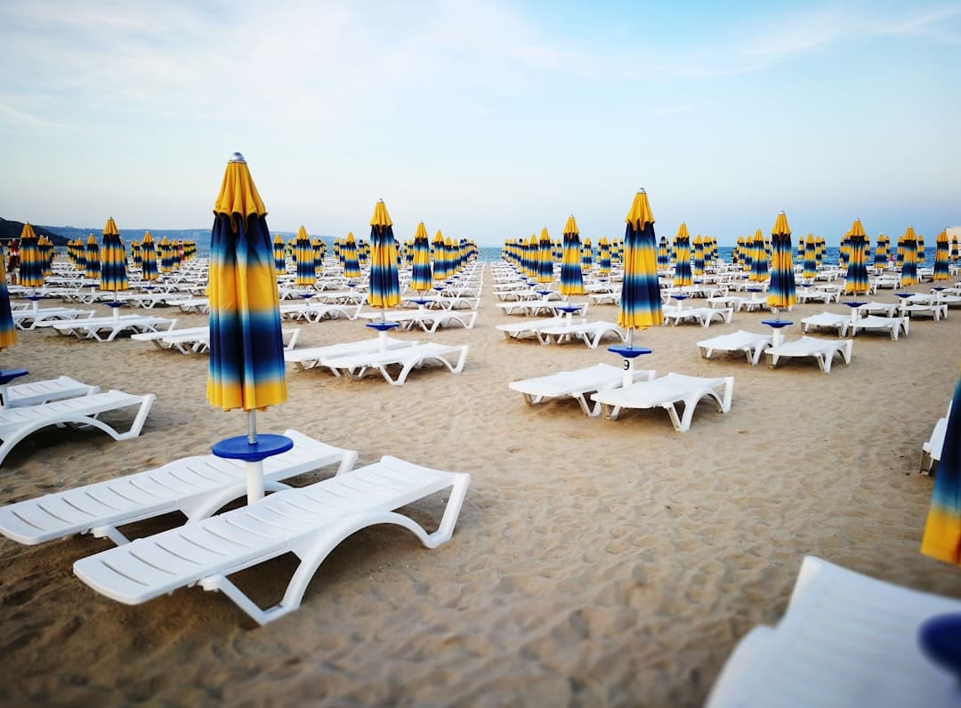 Puste leżaki na piaszczystej plaży z parasolami.