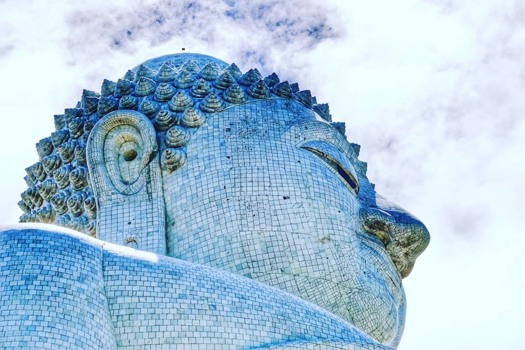 Monumentalna mozaikowa statua Buddy, architektura azjatyckiej świątyni, jasne niebo.