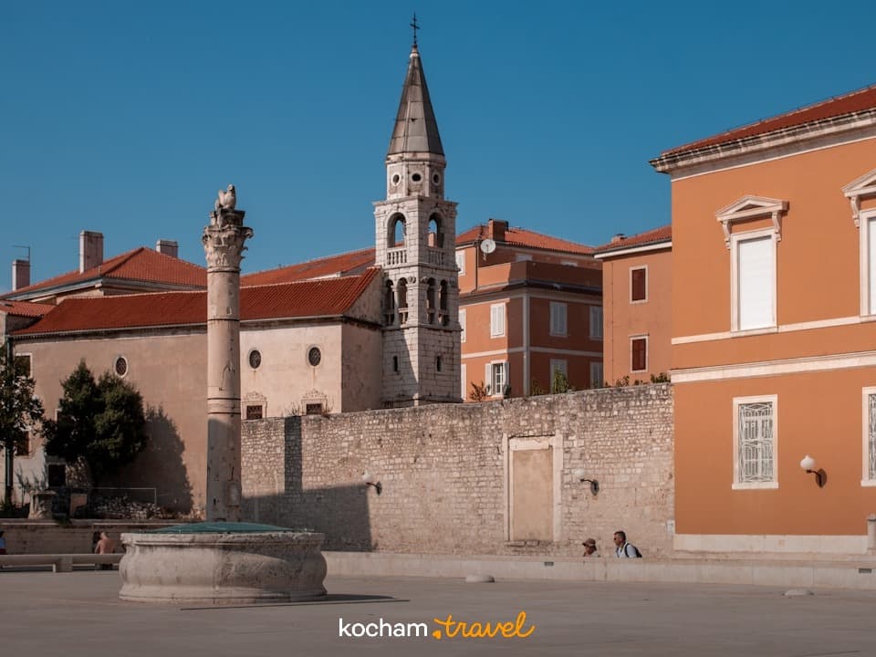 Historyczny plac miejski, dzwonnica, kolumna, stare budynki, słoneczny dzień
