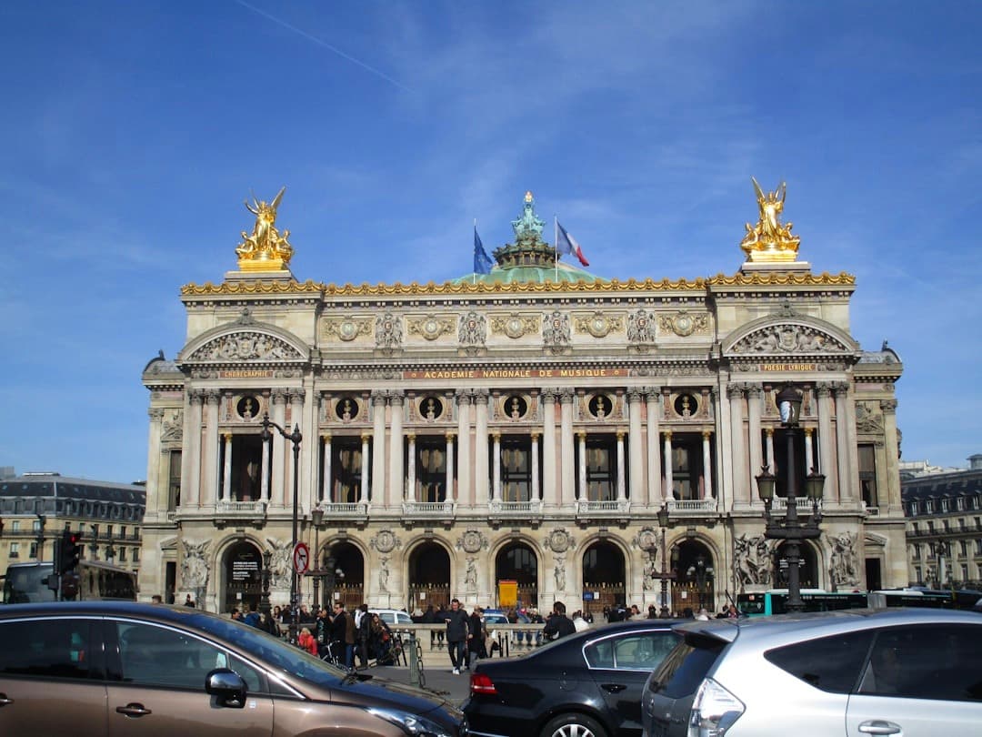 Paryż Opera Garnier, okazała architektura, złote posągi, słoneczny dzień.