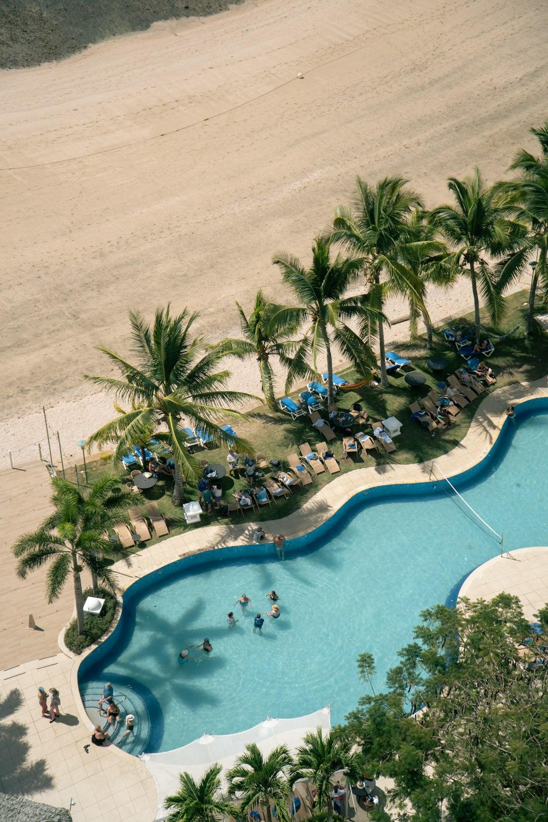Basen, plaża, palmy, ludzie relaksujący się w tropikalnym kurorcie.