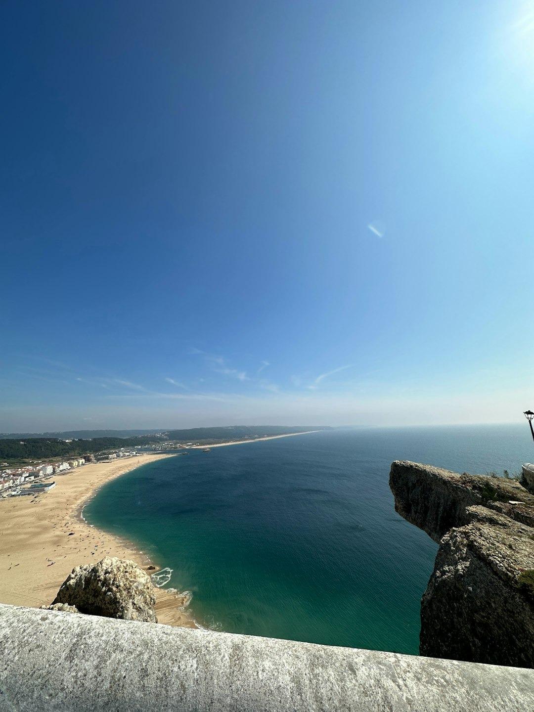 Panoramiczny widok rozległej piaszczystej plaży, turkusowego oceanu i nadmorskiego miasta.