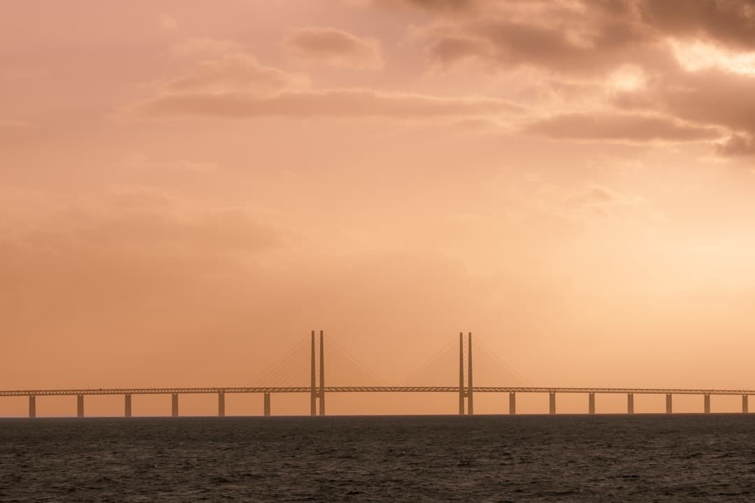 Most Øresund o zachodzie słońca nad wodą, pomarańczowe niebo.