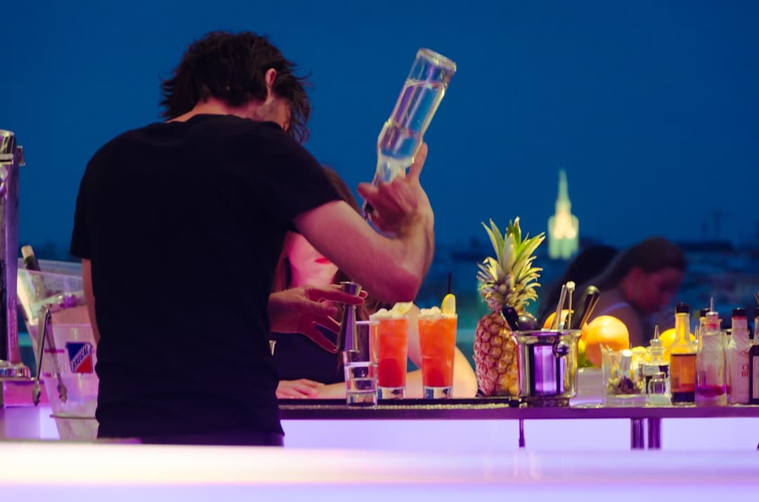 Barman przygotowujący koktajle na nocnym barze z widokiem na miasto.