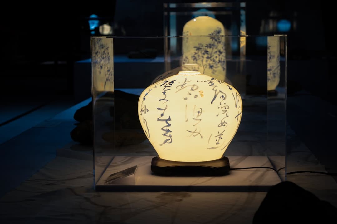 Świecąca ceramiczna lampa z niebieską kaligrafią na wystawie.