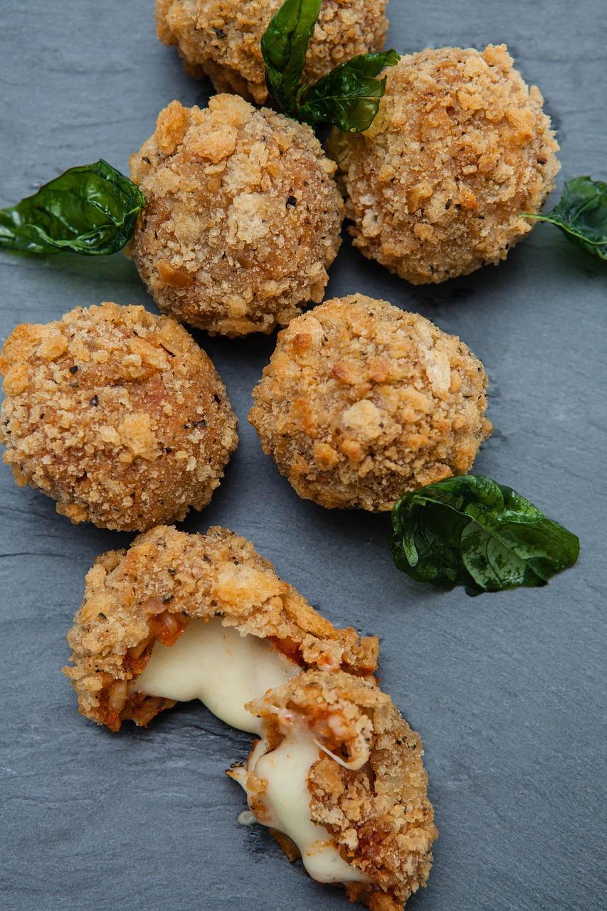 Smażone kulki ryżowe arancini z roztopionym serem i bazylią.