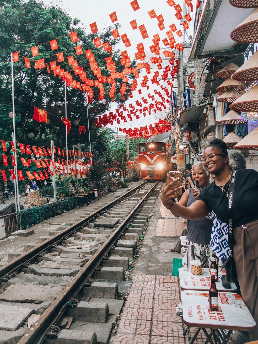 Turyści robiący selfie z nadjeżdżającym pociągiem na Hanoi Train Street.