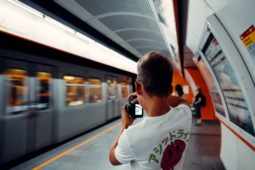 Fotograf na peronie metra robiący zdjęcie pociągowi.