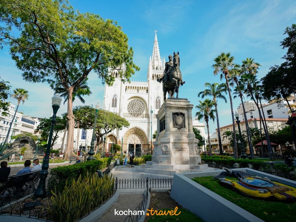 Katedra Metropolitalna Guayaquil, pomnik Simóna Bolívara, słoneczny park miejski z palmami.