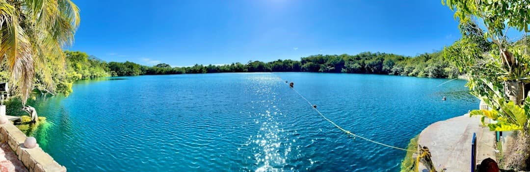 Turkusowe jezioro otoczone tropikalną zielenią w słoneczny dzień.