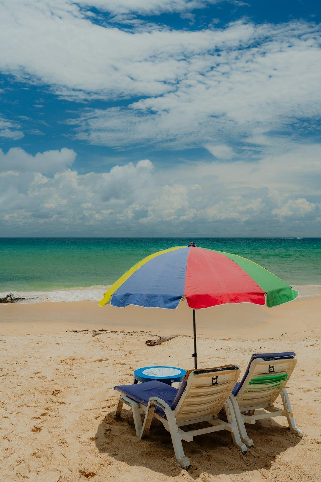Plaża, leżaki, kolorowy parasol, błękitne niebo, morze.