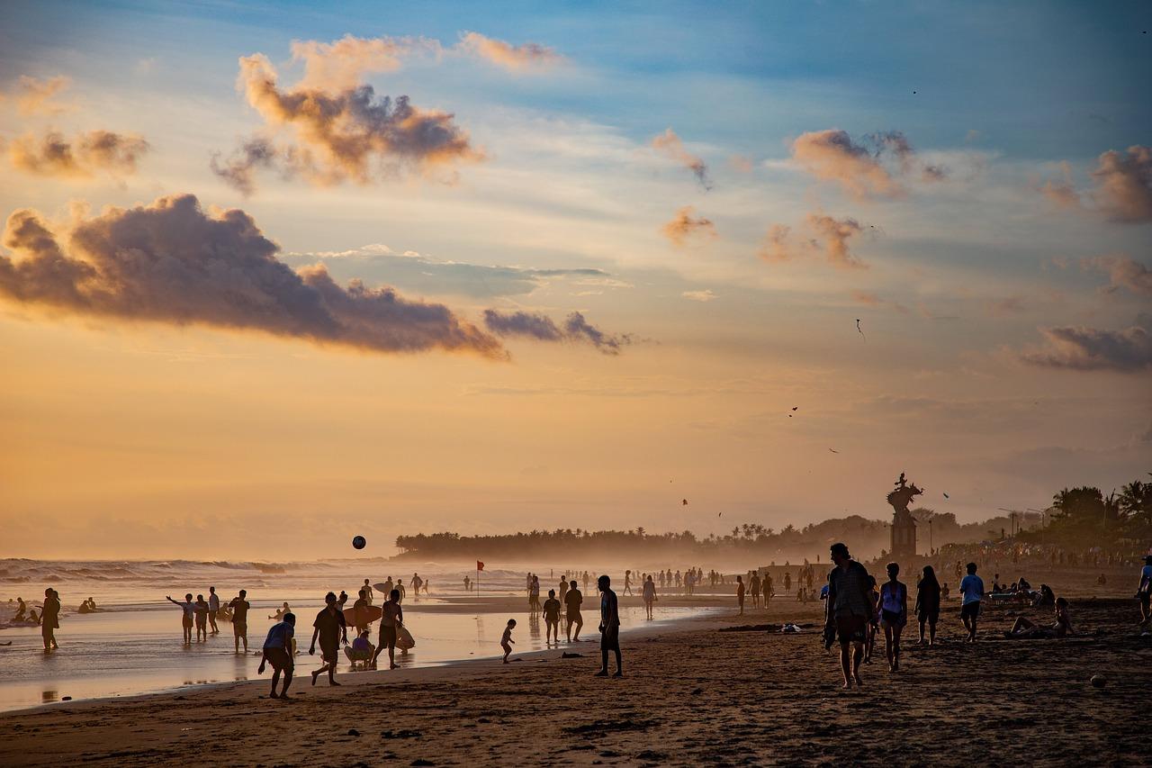 Ludzie bawiący się na plaży o zachodzie słońca, latawce na niebie.