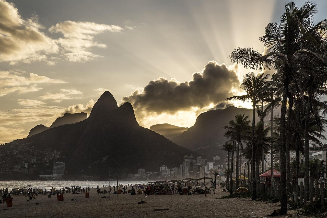 Zachód słońca nad plażą Ipanema z górą Dois Irmãos i palmami.