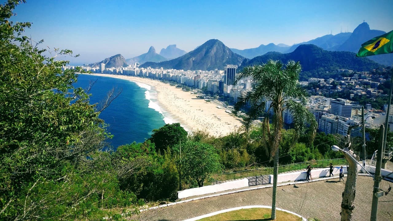 Słoneczna panorama plaży Copacabana, miasta Rio de Janeiro i gór.