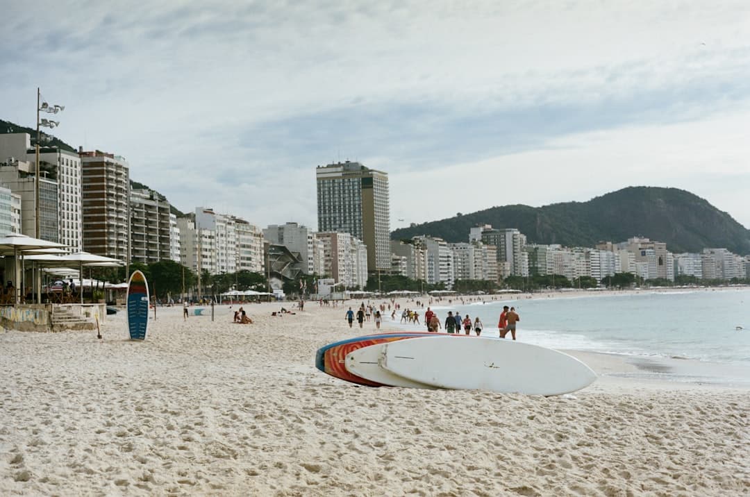Plaża Copacabana z ludźmi, deskami surfingowymi i miastem w tle.