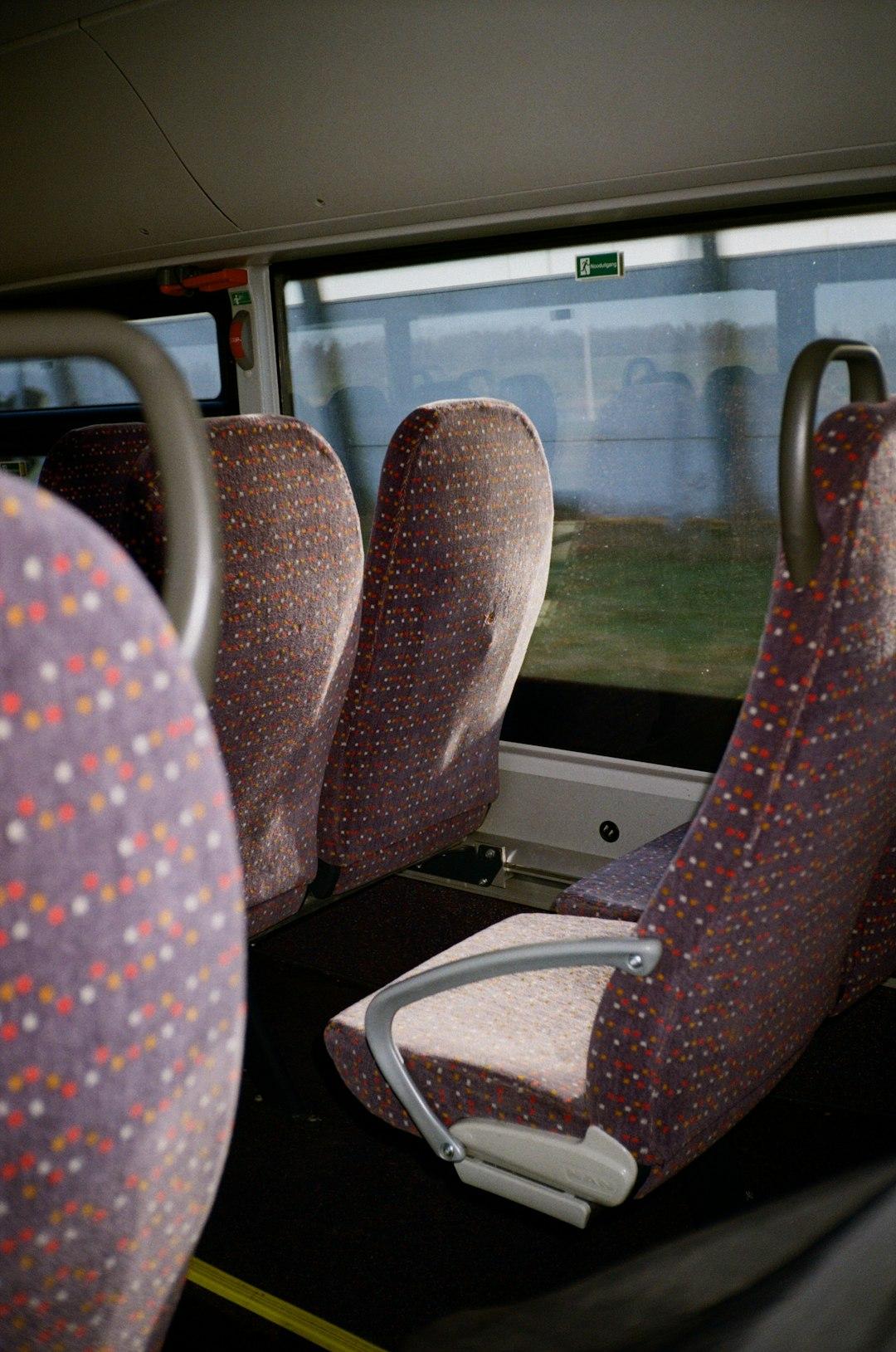 Puste, wzorzyste siedzenia w autobusie, widok krajobrazu przez okno.
