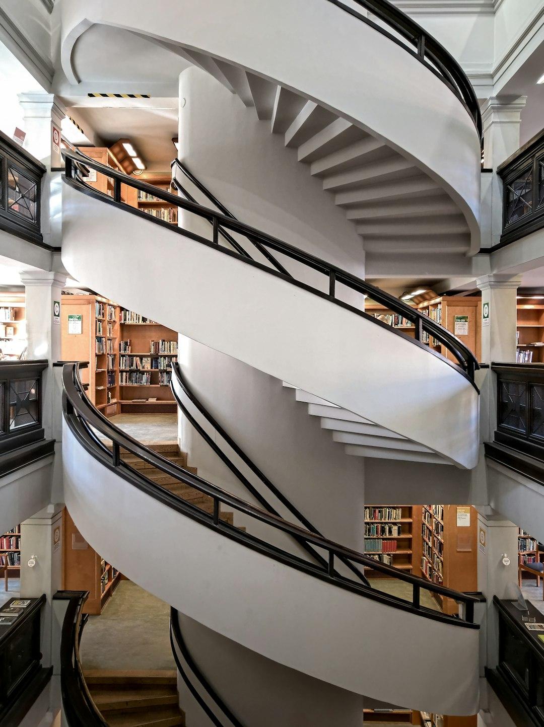 Eleganckie spiralne schody w nowoczesnej bibliotece z regałami książek.