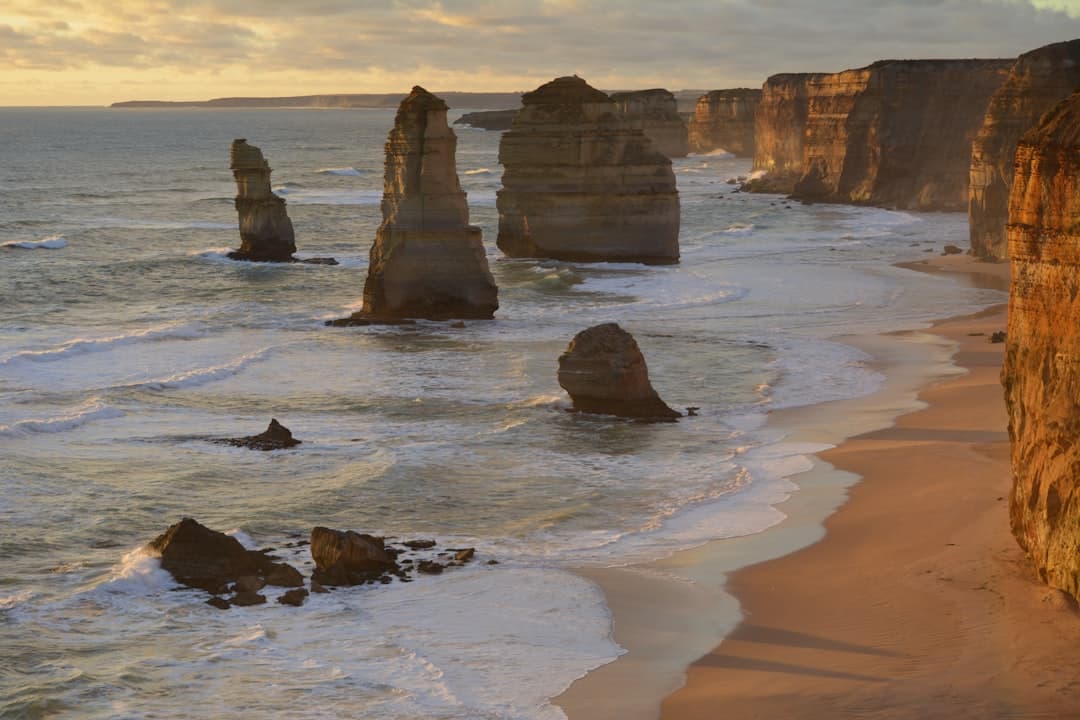 Skały Dwunastu Apostołów, piaszczysta plaża i klify o zachodzie słońca w Australii.