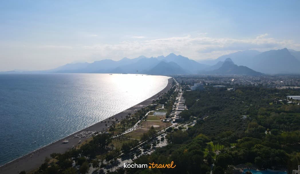 Słoneczna panorama plaży, morza, miasta i odległych gór.