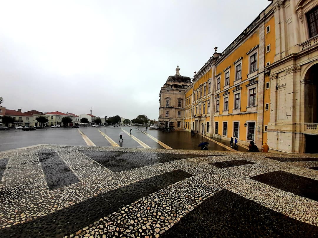 Pałac Narodowy w Mafrze, mokry brukowany plac, deszczowy pochmurny dzień.