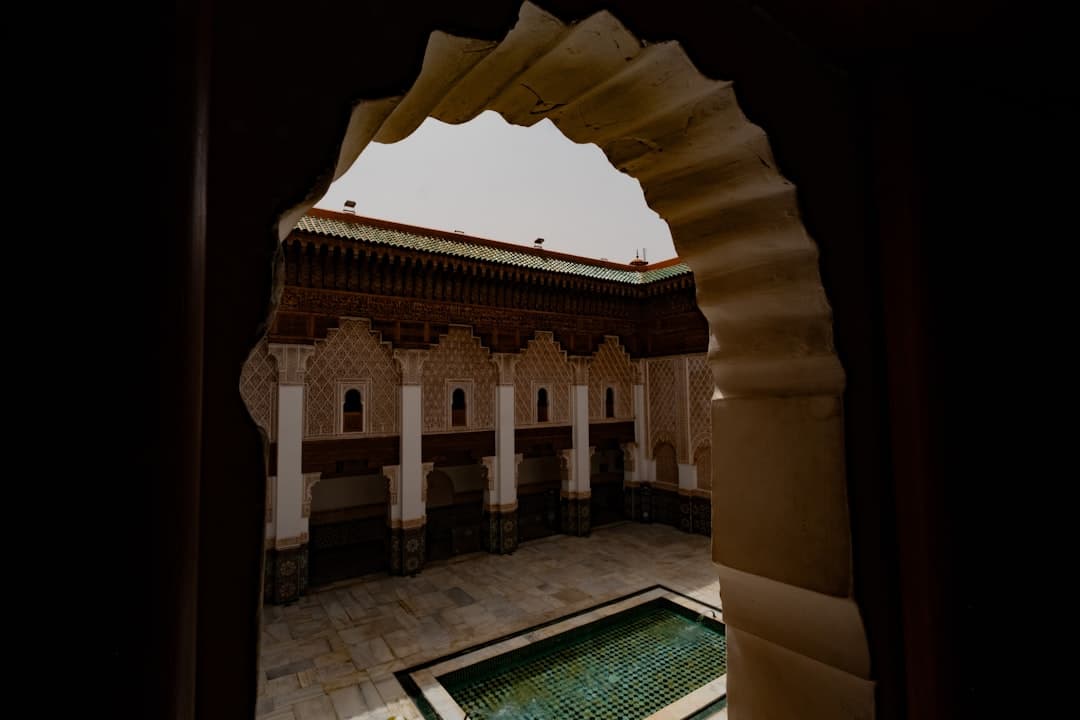 Marokański dziedziniec z basenem, misterną architekturą islamską i łukiem.
