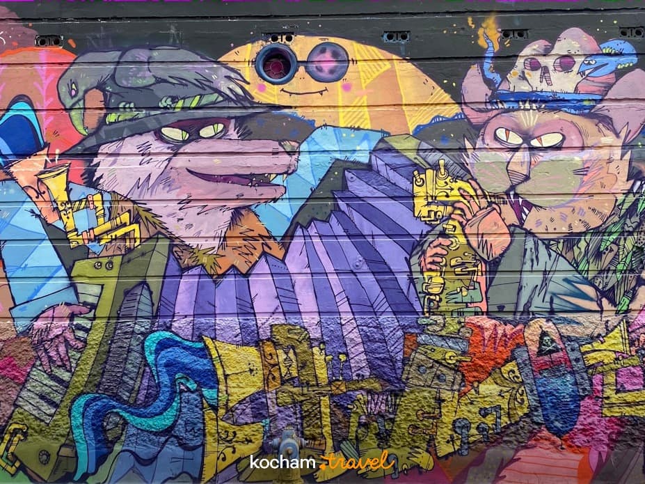 Żywe graffiti na ścianie, antropomorficzne postacie grające, sztuka miejska.