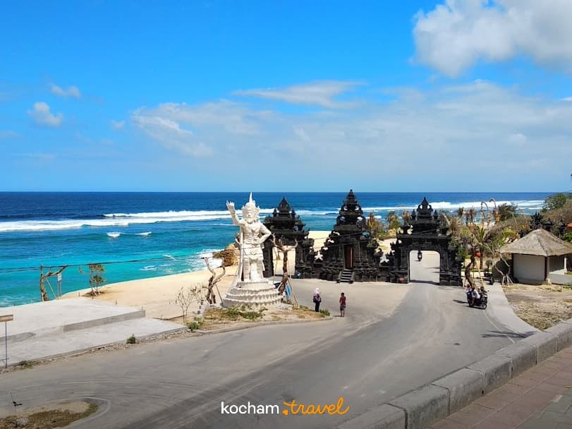 Brama świątynna, biała statua, turkusowa woda, plaża, Bali.
