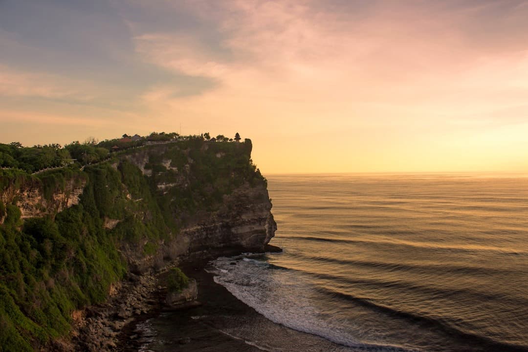 Malowniczy widok na klif Uluwatu i świątynię podczas zachodu słońca.