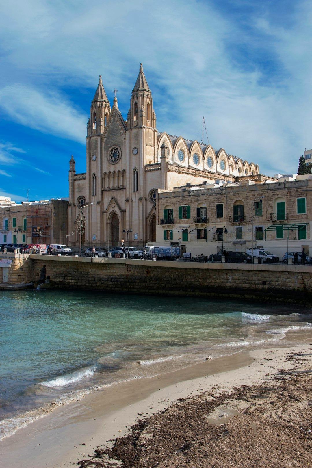 Kościół Balluta, Malta, turkusowa zatoka, piaszczysta plaża, słoneczny dzień.