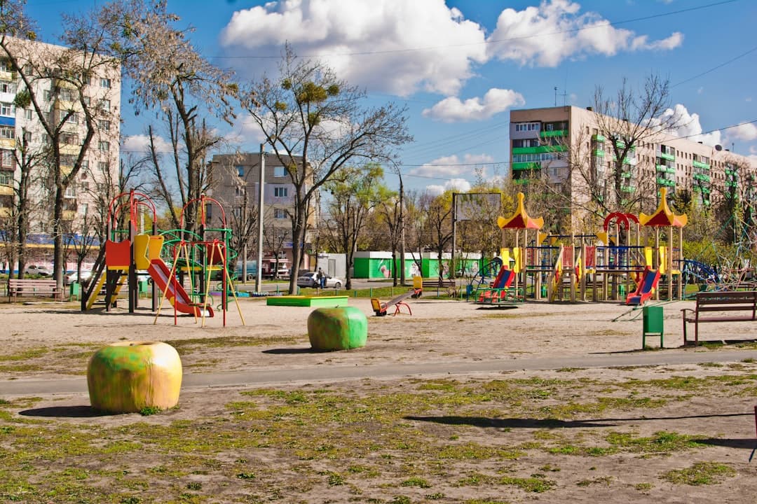 Plac zabaw huśtawki zjeżdżalnie bloki mieszkalne drzewna sceneria.