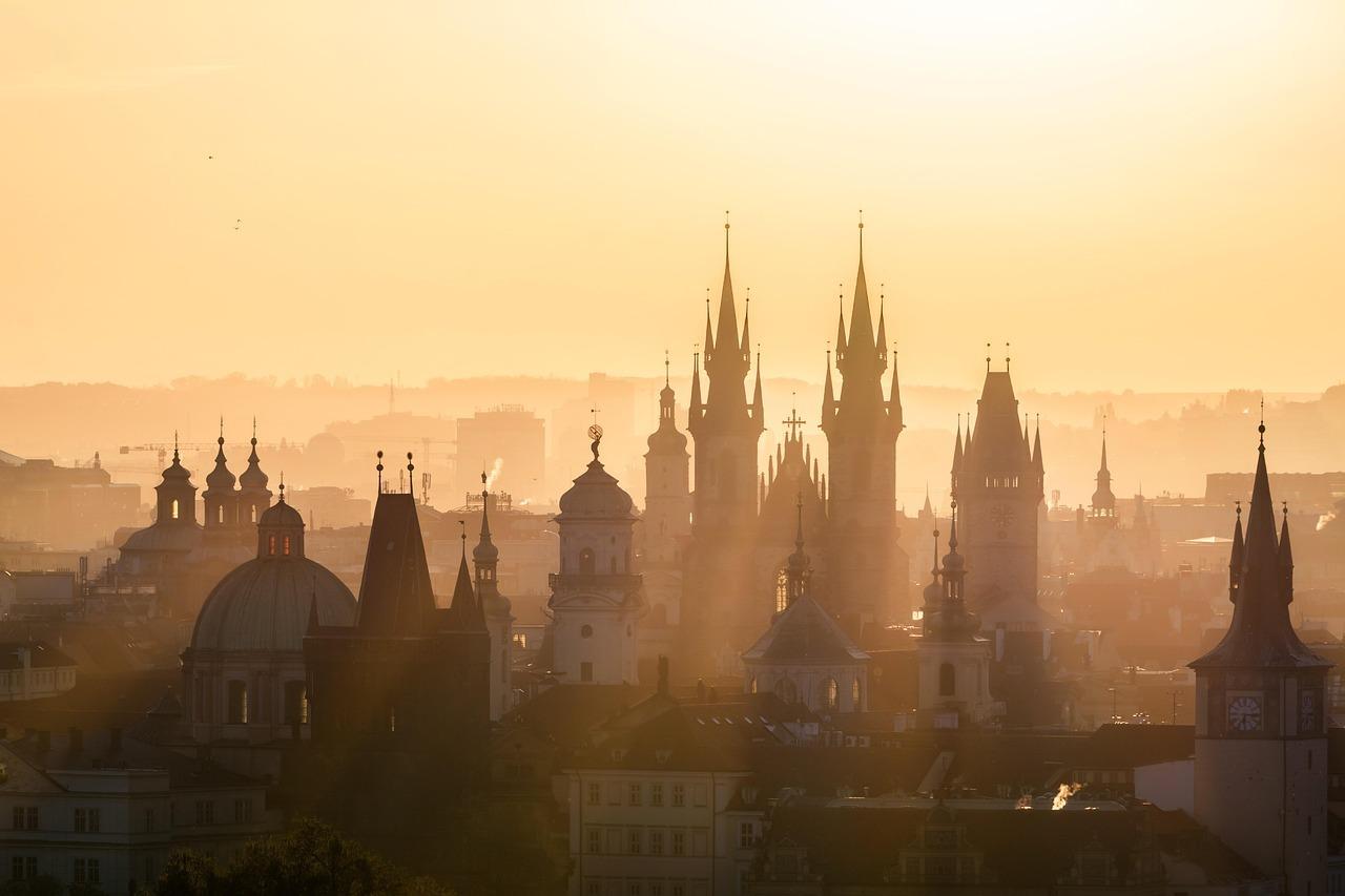 Praga panorama miasta, zabytkowe wieże, złote światło o wschodzie słońca.