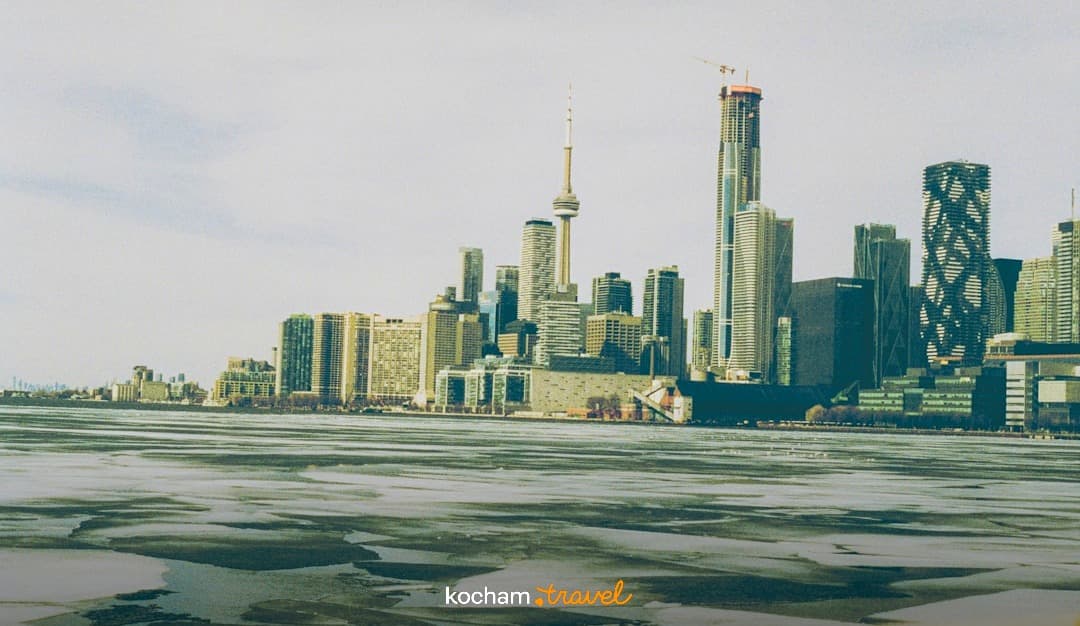 Zimowy widok na panoramę Toronta z wieżą CN Tower i zamarzniętym jeziorem.