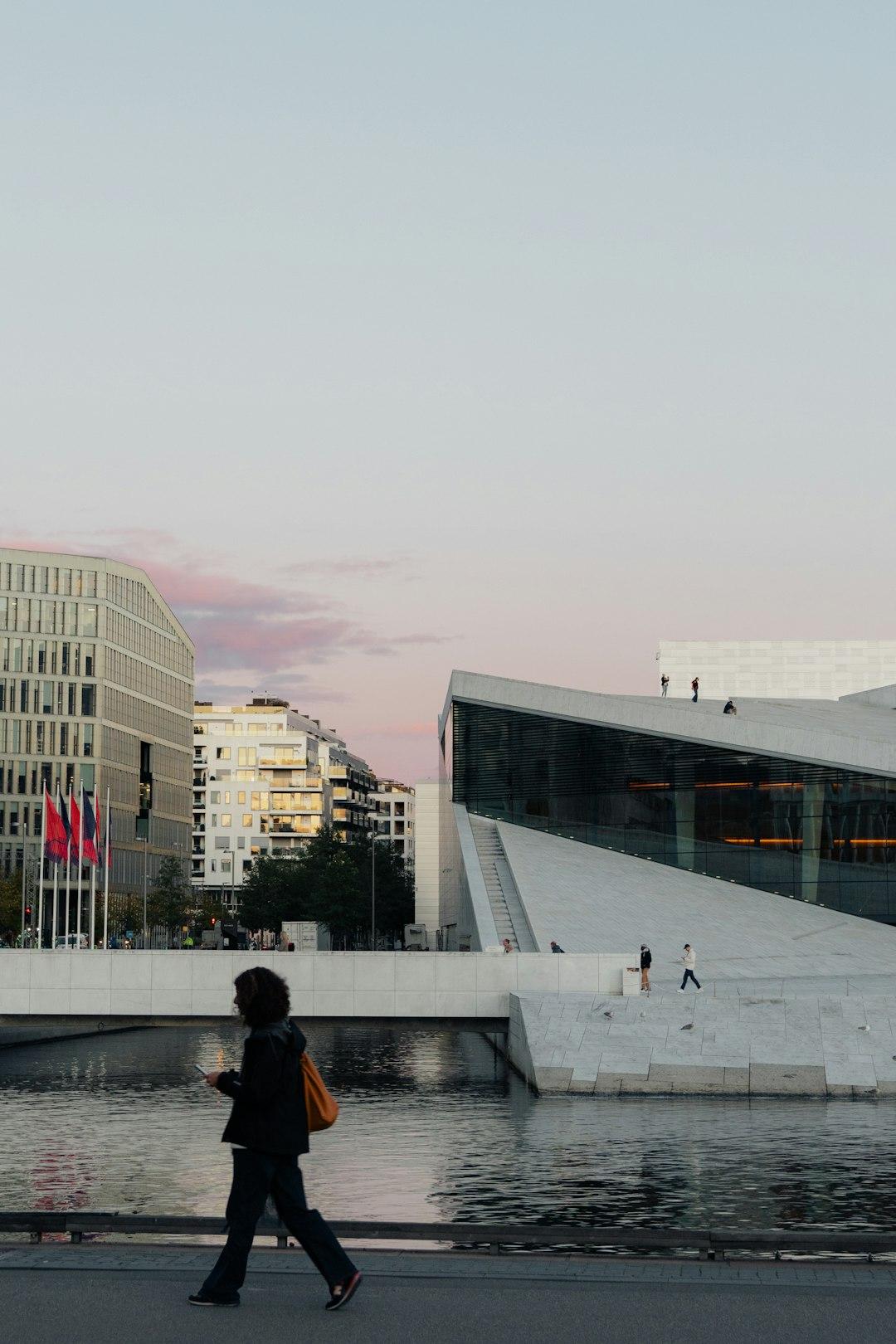 Oslo: Opera, nowoczesne budynki, osoba spacerująca wzdłuż nabrzeża o zmierzchu.