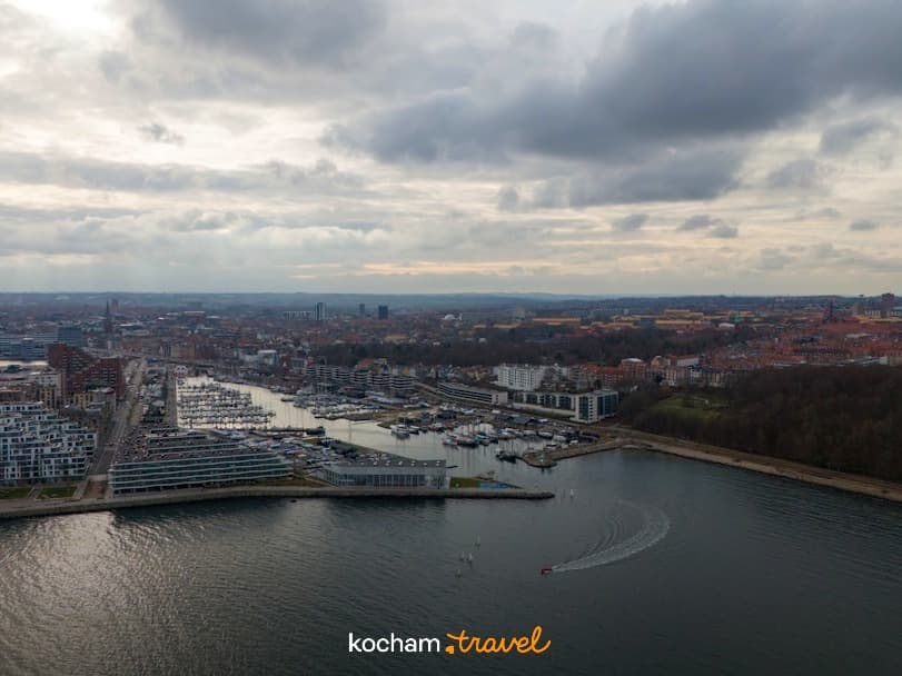 Panorama portu miejskiego z mariną, nowoczesną zabudową i pochmurnym niebem.