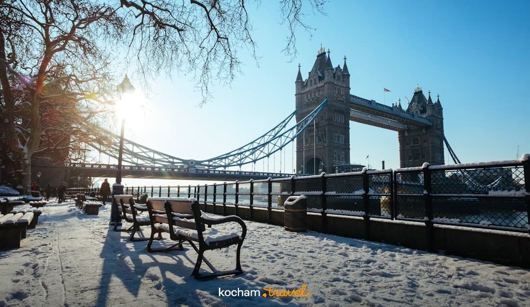 Ikoniczny Tower Bridge w Londynie, zaśnieżony park, słońce.