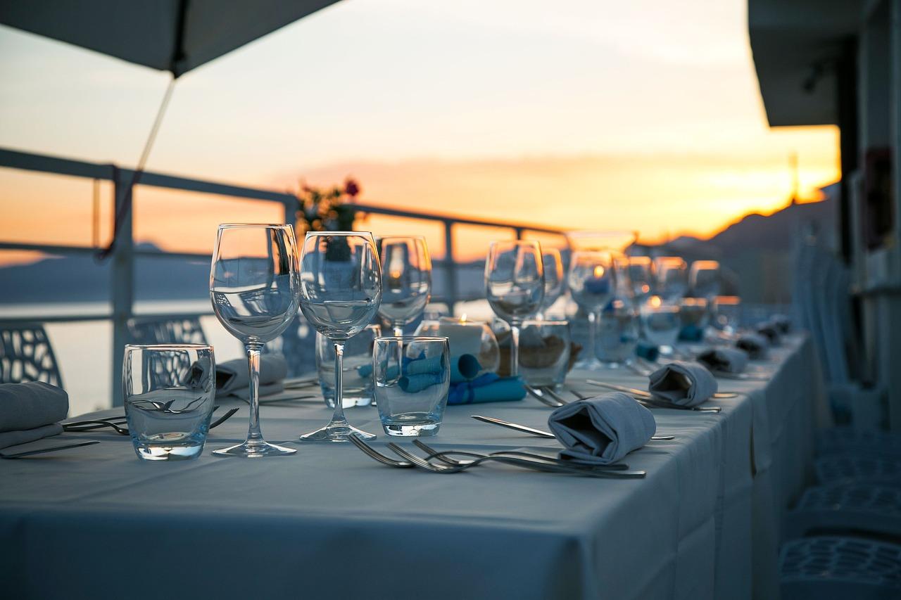 Elegancko zastawiony stół restauracyjny z widokiem na zachód słońca nad morzem.