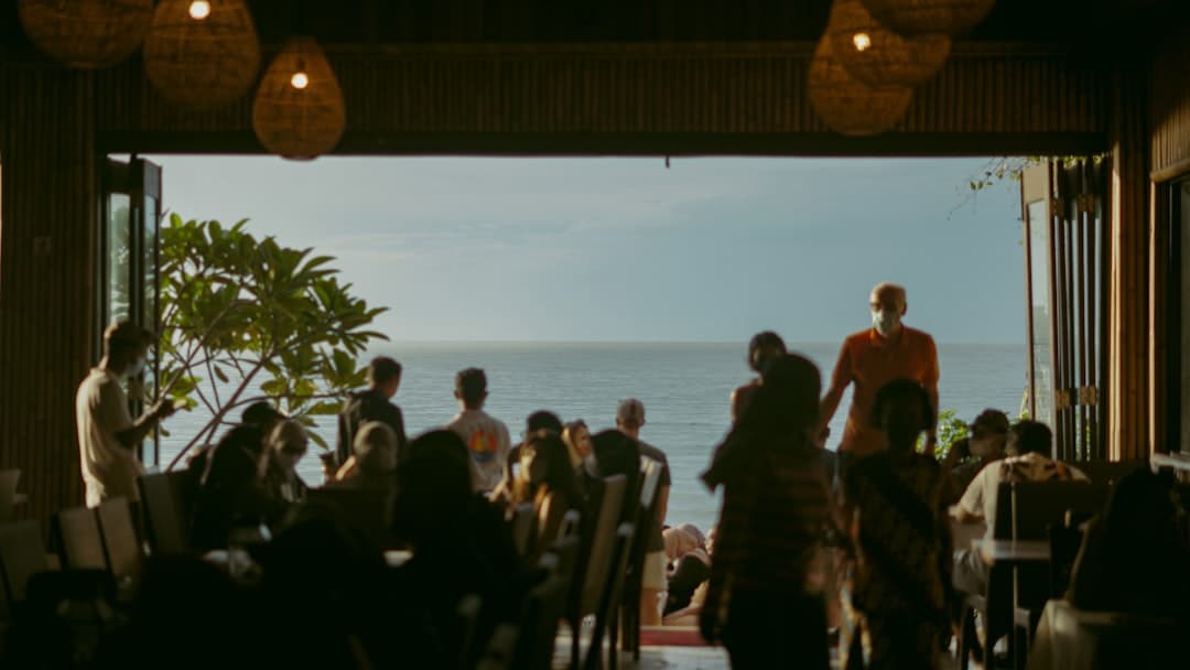 Ludzie w restauracji z widokiem na ocean i wiszącymi lampami.