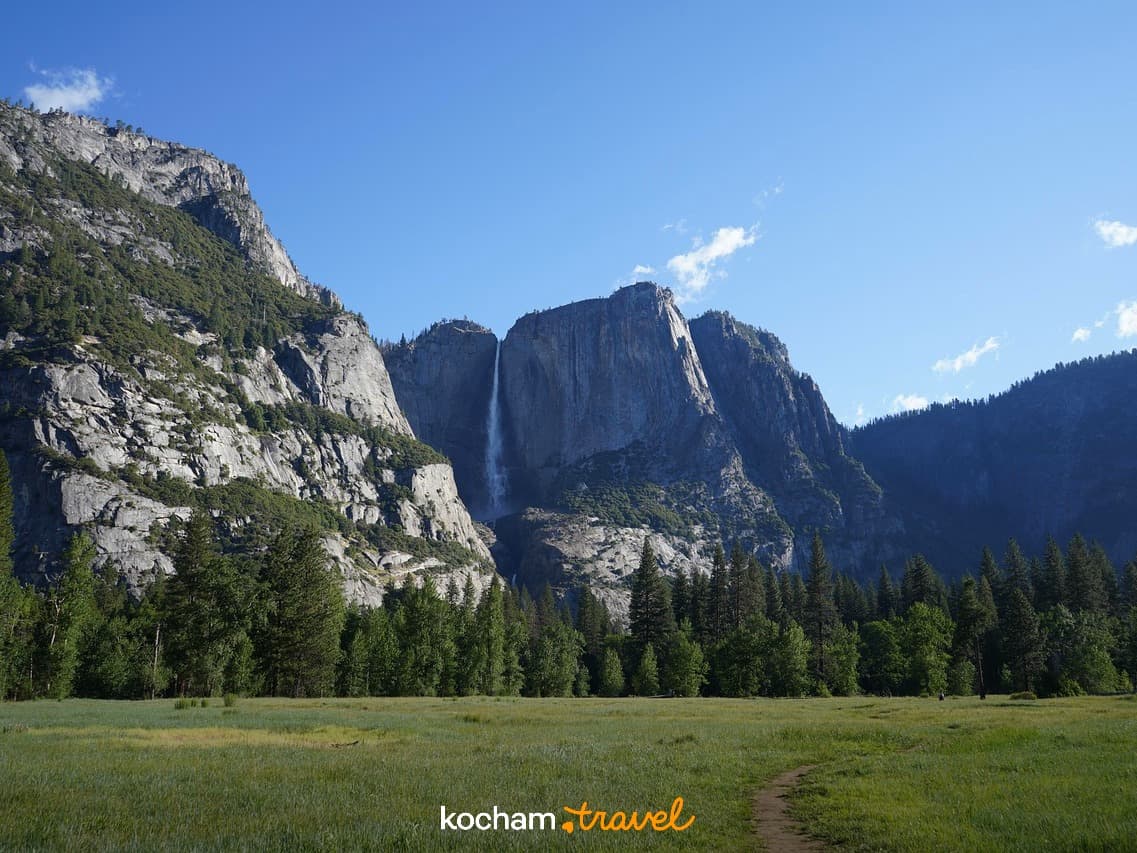 Majestatyczny Wodospad Yosemite, zielona łąka, skalne klify, słoneczny dzień.